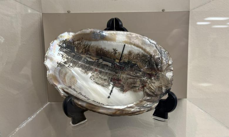 This mussel shell on display in the museum was painted in 1920. The image on it shows a button factory that was in De Valls Bluff. 